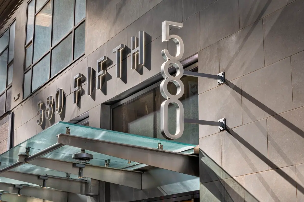 The brushed steel letters 580 FIFTH above the glass canopy over the entrance of 580 Fifth Avenue.